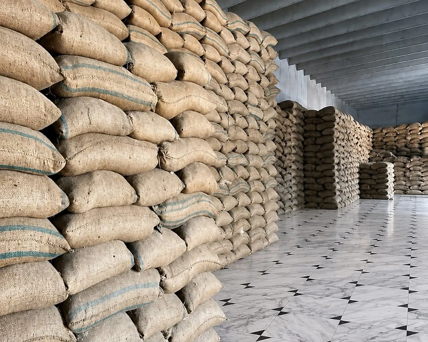 Rows of stacked jute bags in a Green International Rice storage hall