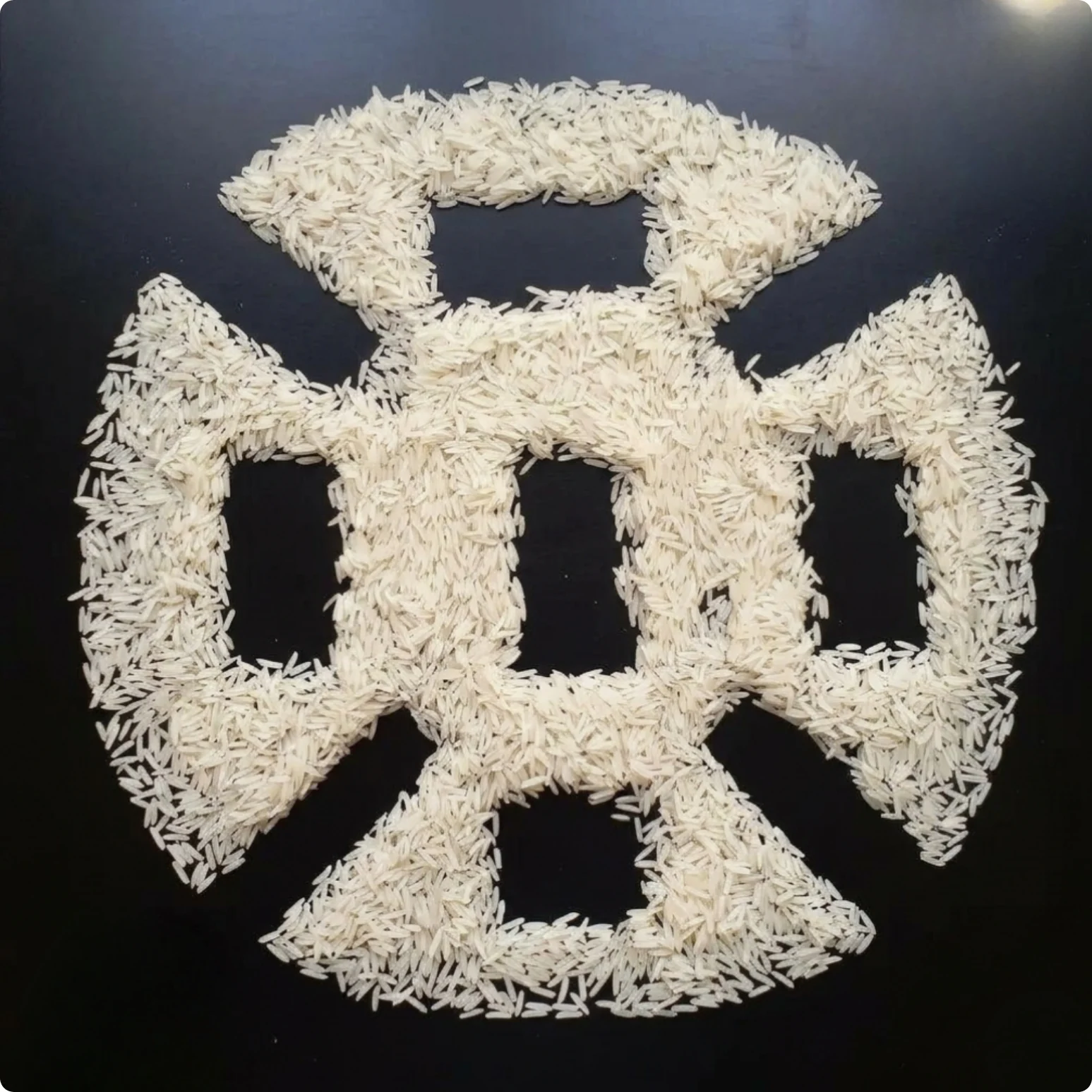 Milled rice grains arranged as an emblem on a dark surface